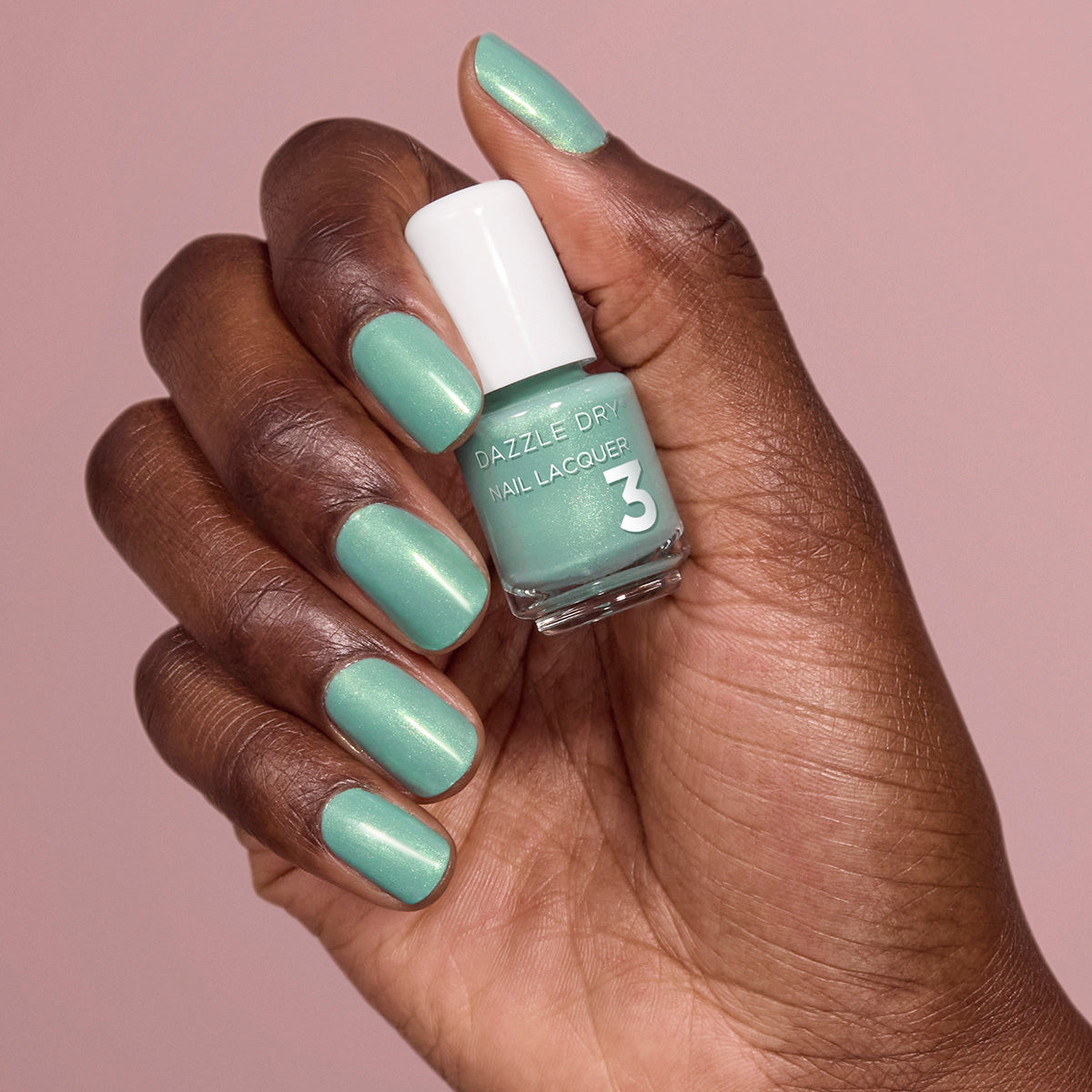 Hand with In Season painted on nails holding mini lacquer bottle.