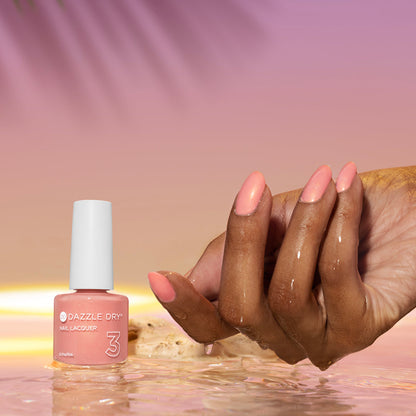 Hand with Sunset Glow painted on nails next to nail lacquer bottle