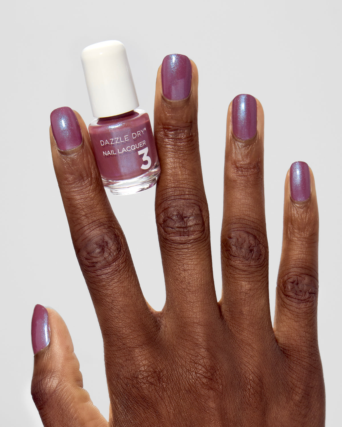 Hand with School Spirit painted on nails holding mini lacquer bottle