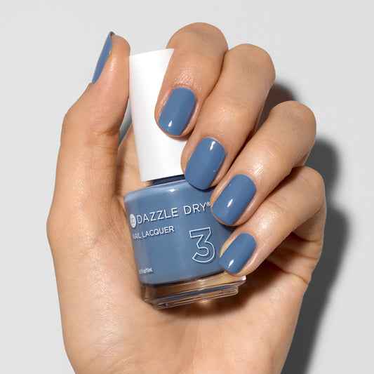 Hand with Varsity Blues painted on nails holding lacquer bottle