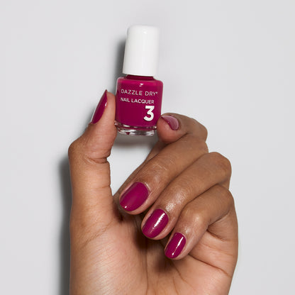 Hand with Raspberry Rush painted on nails holding mini lacquer botte