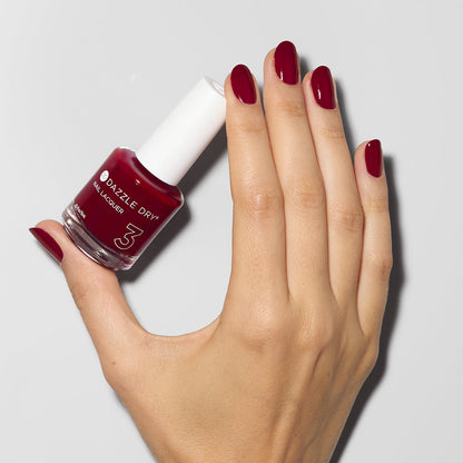 Hand with Fast Track Cherry painted on nails holding lacquer bottle