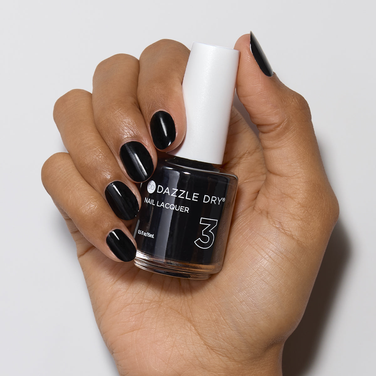 Hand with Midnight Express painted on nails holding lacquer bottle