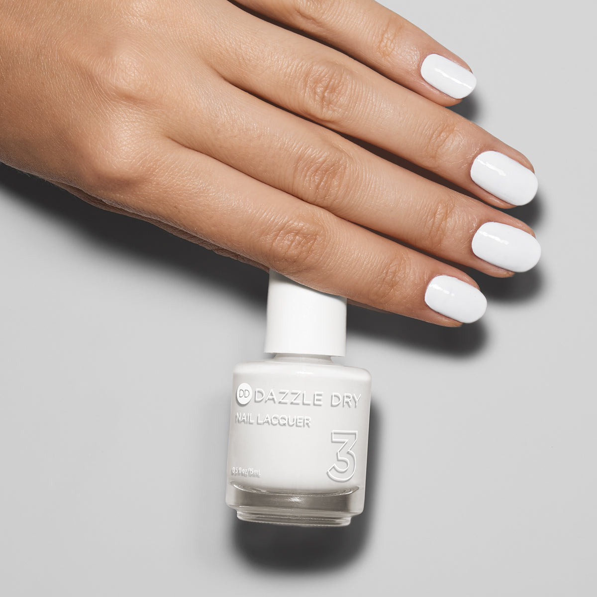 Hand with White Lightning painted on nails holding lacquer bottle