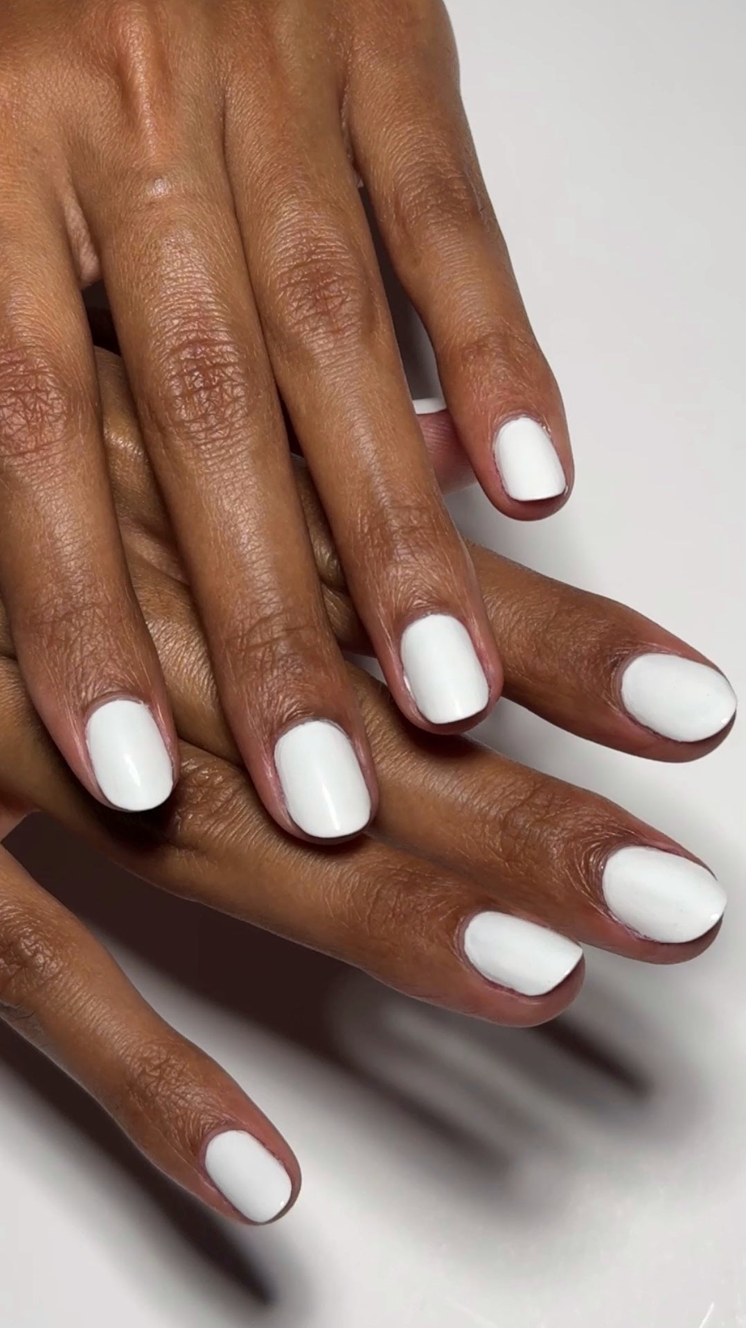 Close-up of hands one over the other. showing nails painted with Dazzle Dry White Lightning polish