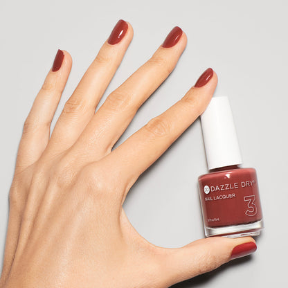 Hand with Cinnamon Spice painted on nails holding nail lacquer bottle