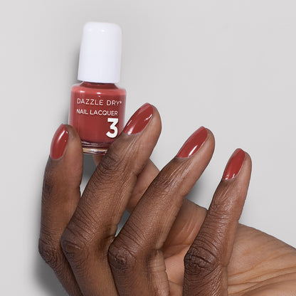 Hand with Cinnamon Spice painted on nails holding mini nail lacquer bottle