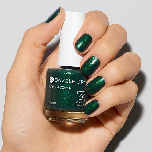 Hand with Evergreen painted on nails holding lacquer bottle