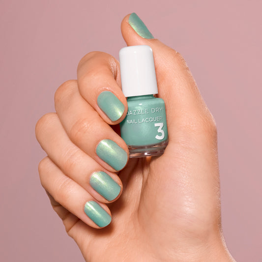 Hand with In Season painted on nails holding mini lacquer bottle.