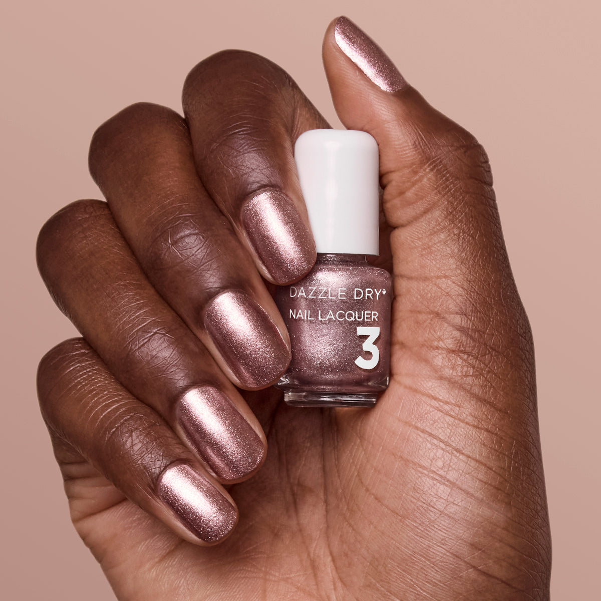 Hand with Out N' About painted on nails holding mini lacquer bottle.