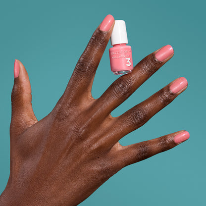 Hand with Cherry Blossom painted on nails holding mini lacquer bottle