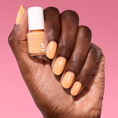 Hand with Creamsicle Sorbet painted on nails holding mini lacquer bottle.