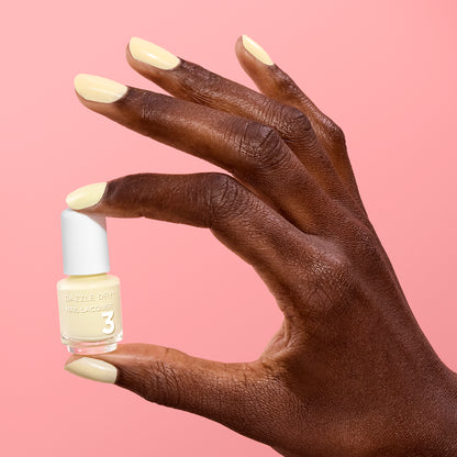 Hand with Sundress painted on nails holding mini lacquer bottle