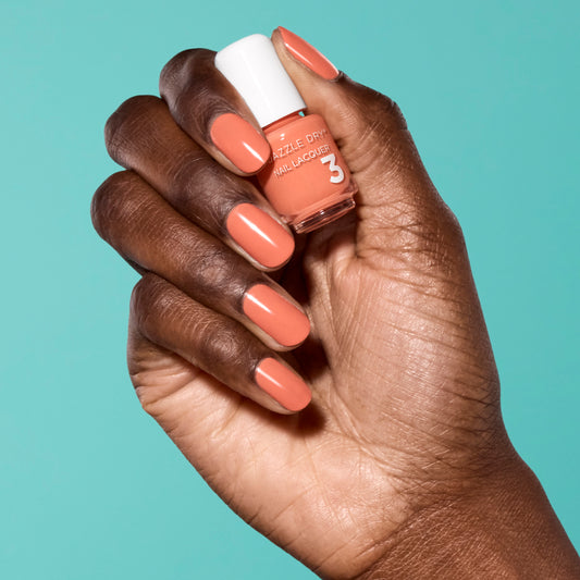 Hand with Round Trip painted on nails holding mini size lacquer bottle