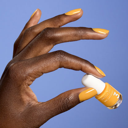 Hand with Go Go Mango painted on nails holding mini nail lacquer bottle