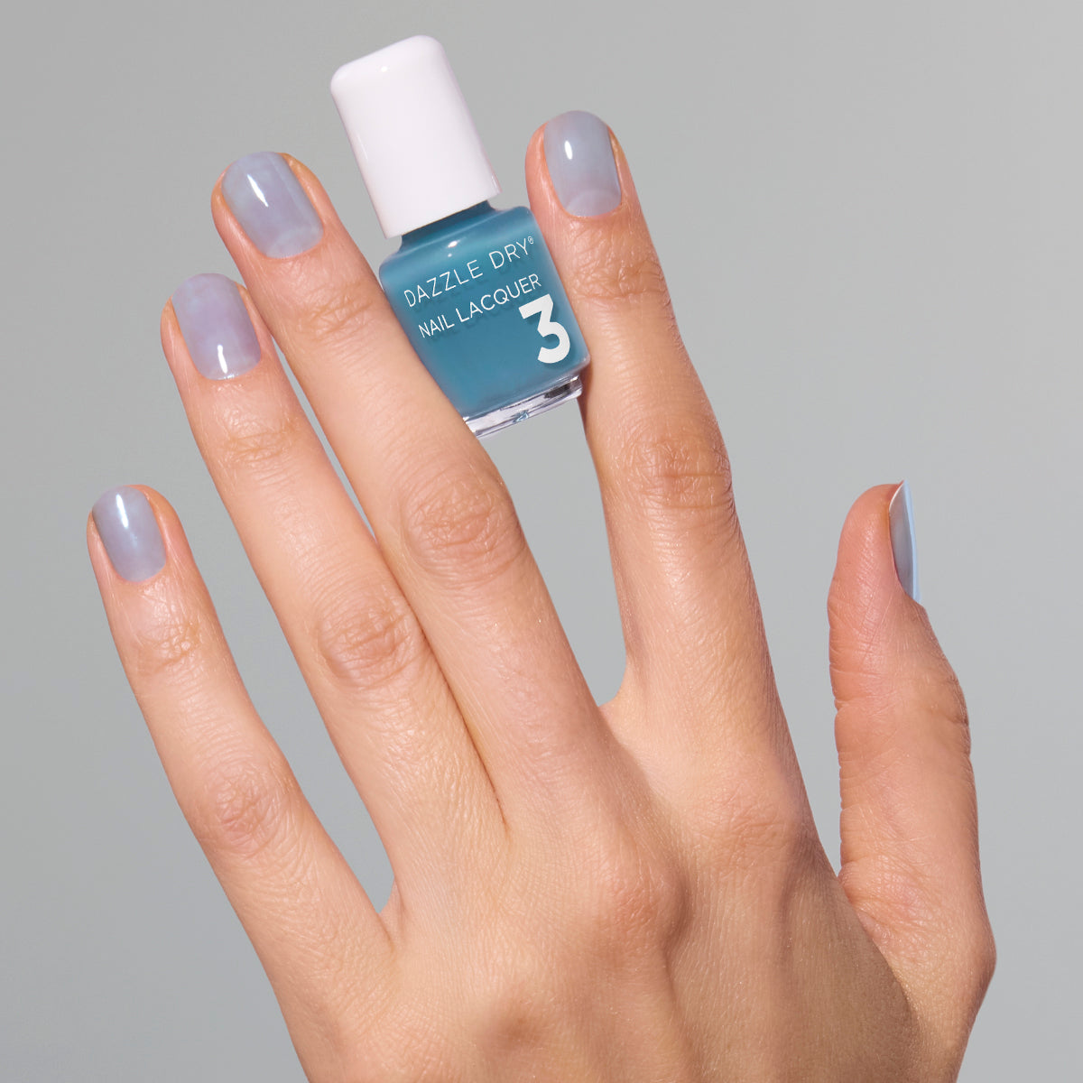 Hand with Candy Coated painted on nails holding mini lacquer bottle.