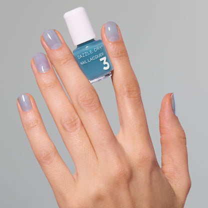 Hand with Candy Coated painted on nails holding mini lacquer bottle.