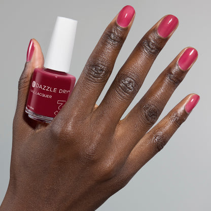 Hand with Ring Toss painted on nails holding full size lacquer bottle