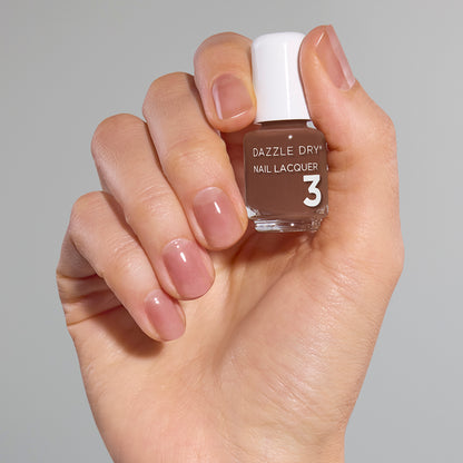 Hand with Toffee Crunch painted on nails holding mini nail lacquer bottle