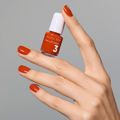 Hand with Orchard painted on nails holding mini lacquer bottle