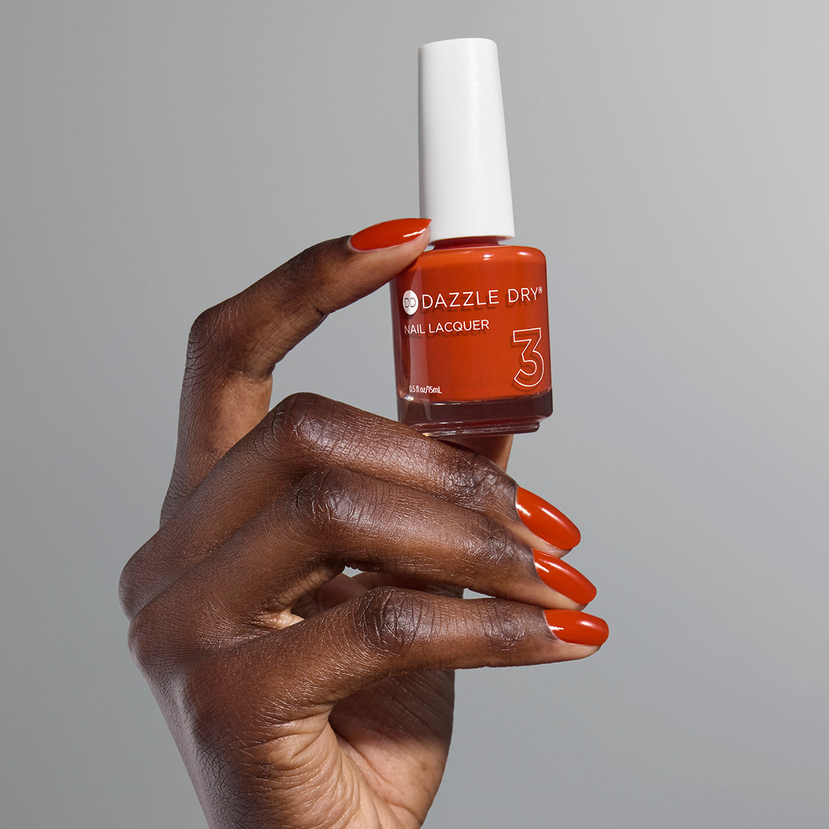 Hand with Orchard painted on nails holding full size lacquer bottle