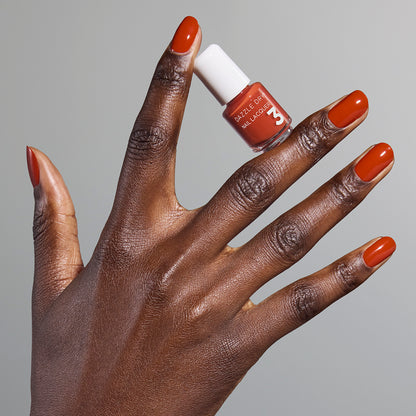 Hand with Orchard painted on nails holding mini lacquer bottle