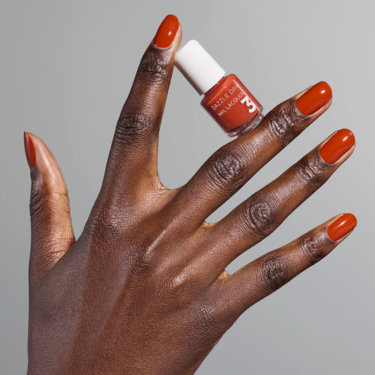 Hand with Orchard painted on nails holding mini lacquer bottle