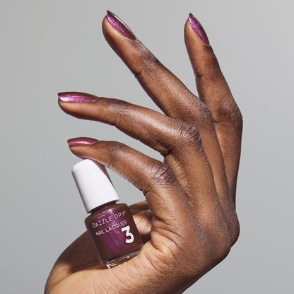 Hand with Spiced Plum painted on nails holding mini lacquer bottle
