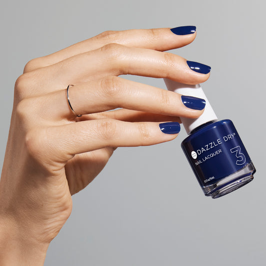 Hand with Midnight Sky painted on nails holding lacquer bottle