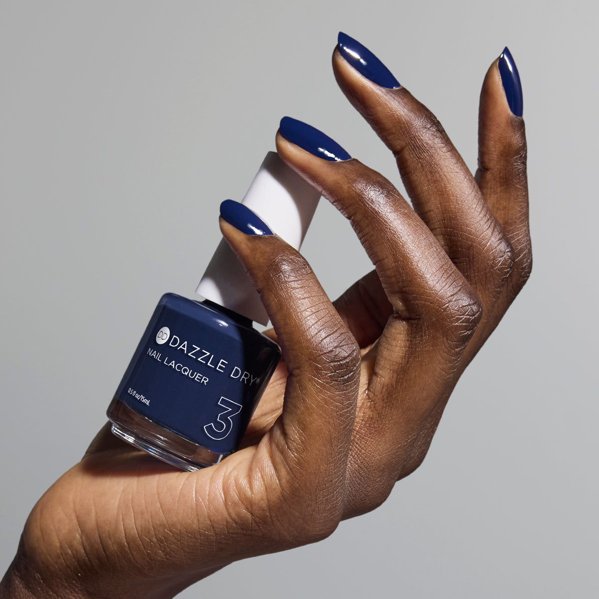 Hand with Midnight Sky painted on nails holding lacquer bottle