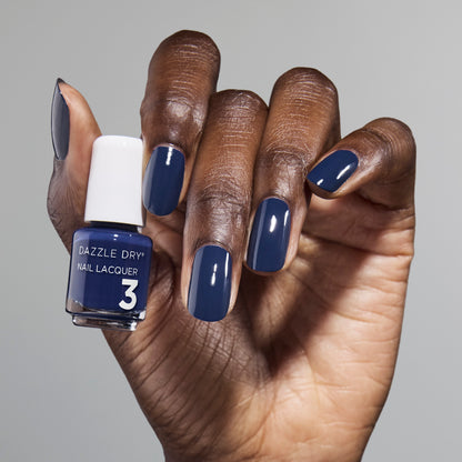 Hand with Midnight Sky painted on nails holding mini lacquer bottle