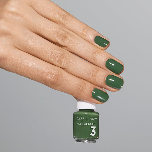 Hand with Fern painted on nails holding mini lacquer bottle