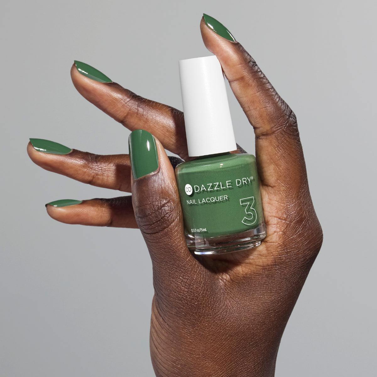 Hand with Fern painted on fingernails holding full size lacquer bottle