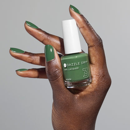 Hand with Fern painted on fingernails holding full size lacquer bottle