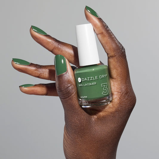 Hand with Fern painted on fingernails holding full size lacquer bottle