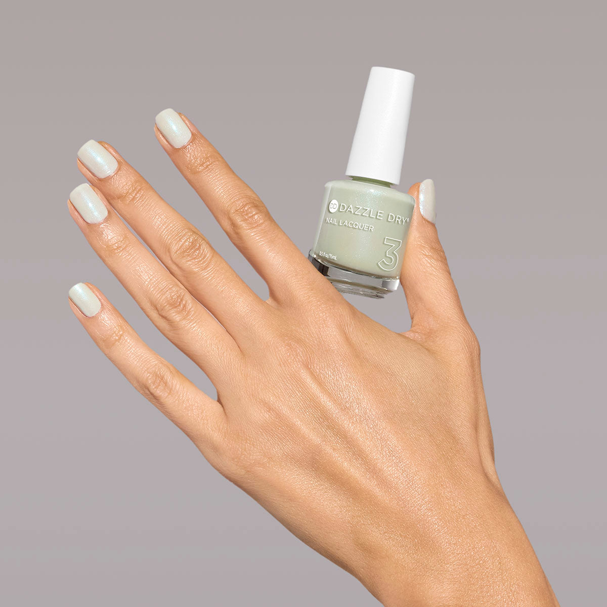 Hand with Embark painted on nails holding full size lacquer bottle