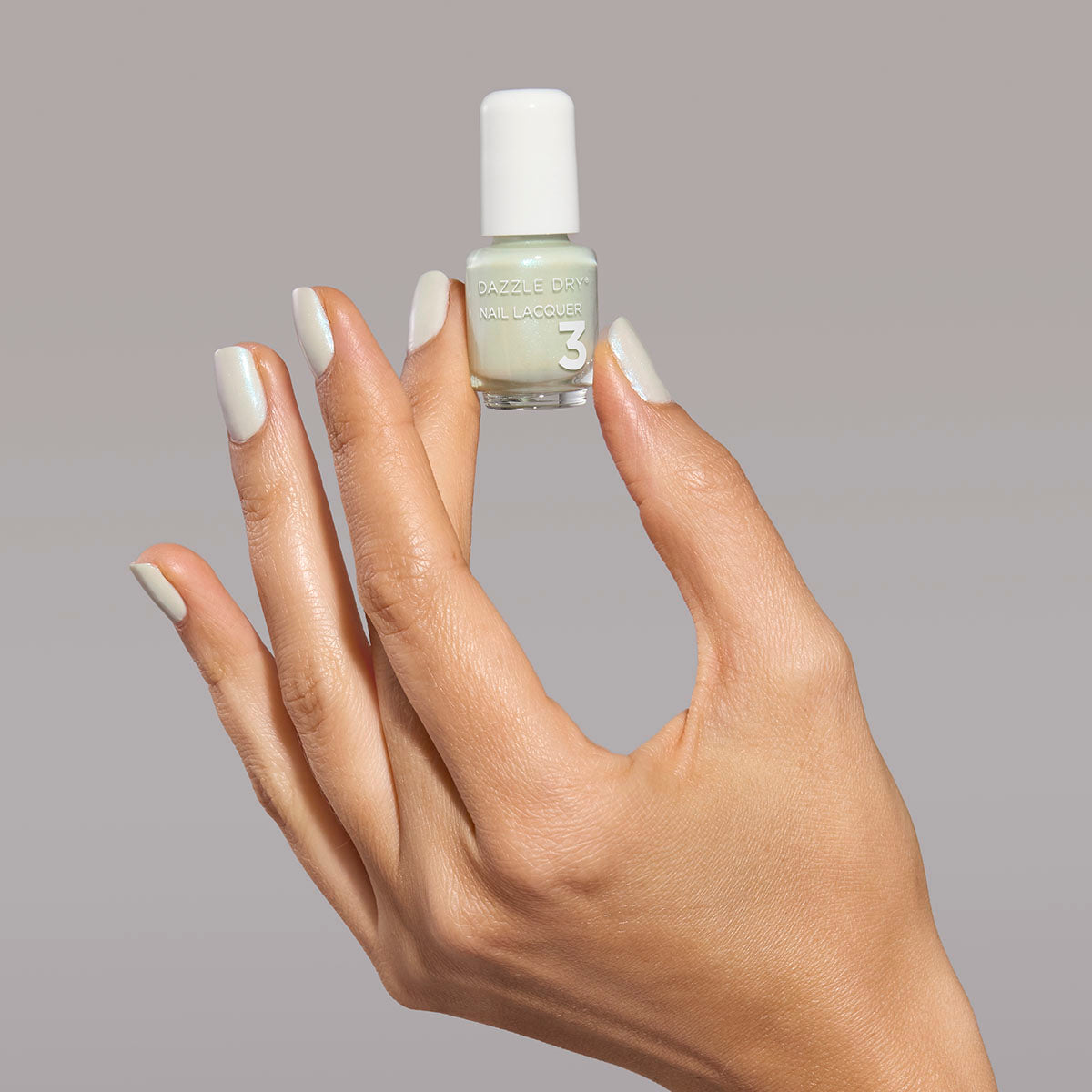 Hand with Embark painted on nails holding mini lacquer bottle