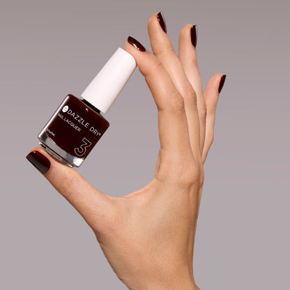 Hand with Mulled Wine painted on nails holding full size nail lacquer