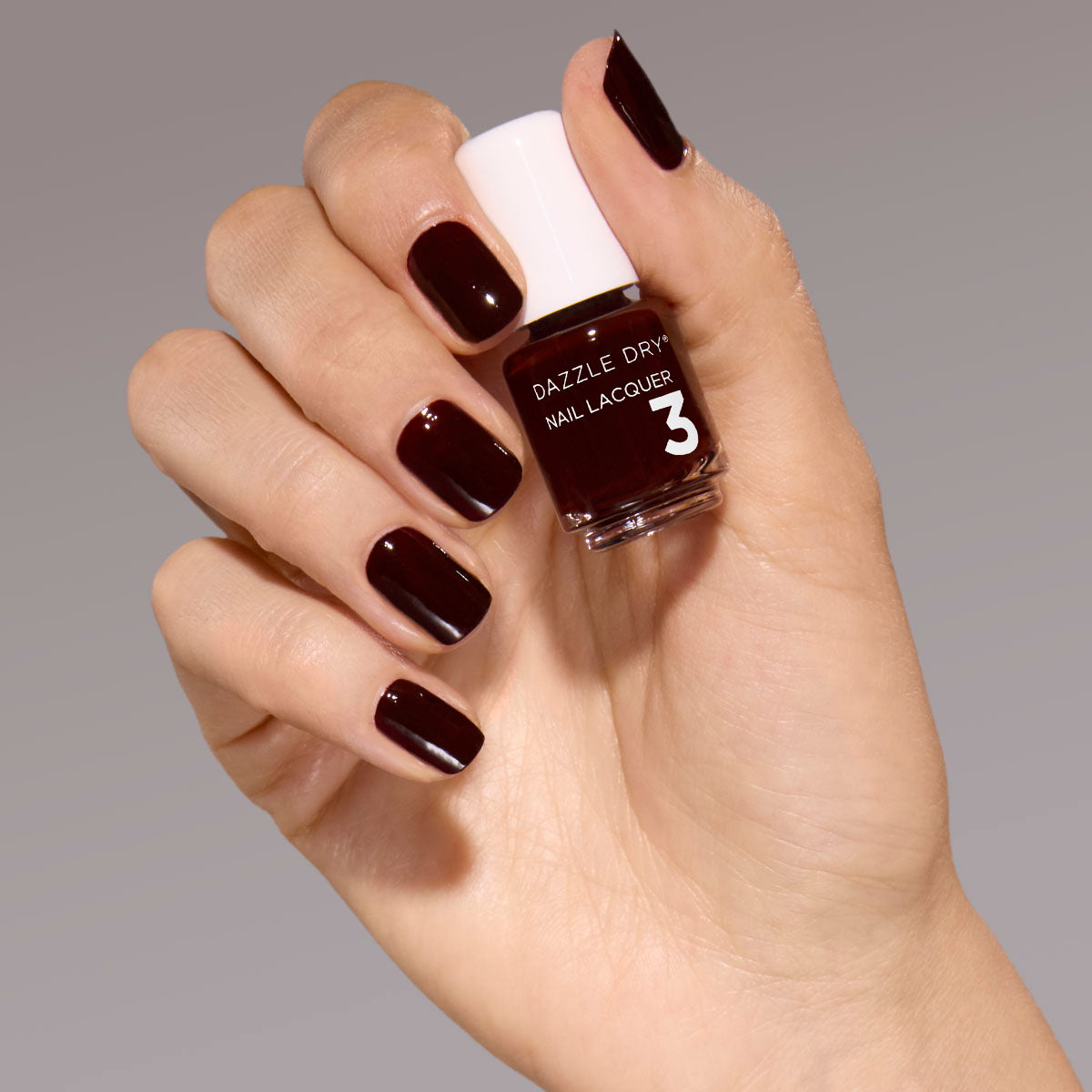 Hand with Mulled Wine painted on nails holding mini nail lacquer