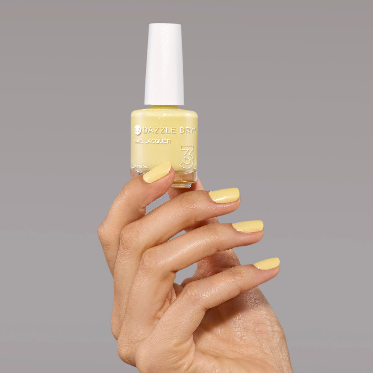 Hand with Solstice painted on nails holding full size lacquer bottle