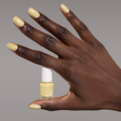 Hand with Solstice painted on nails holding mini lacquer bottle