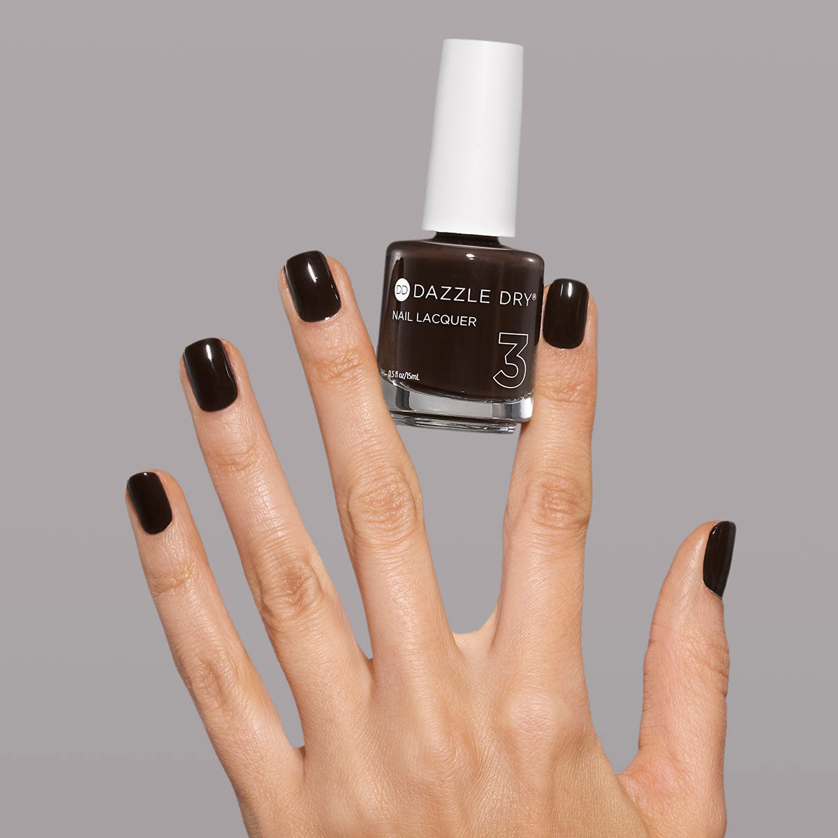 Hand with Haze painted on nails holding full size lacquer bottle