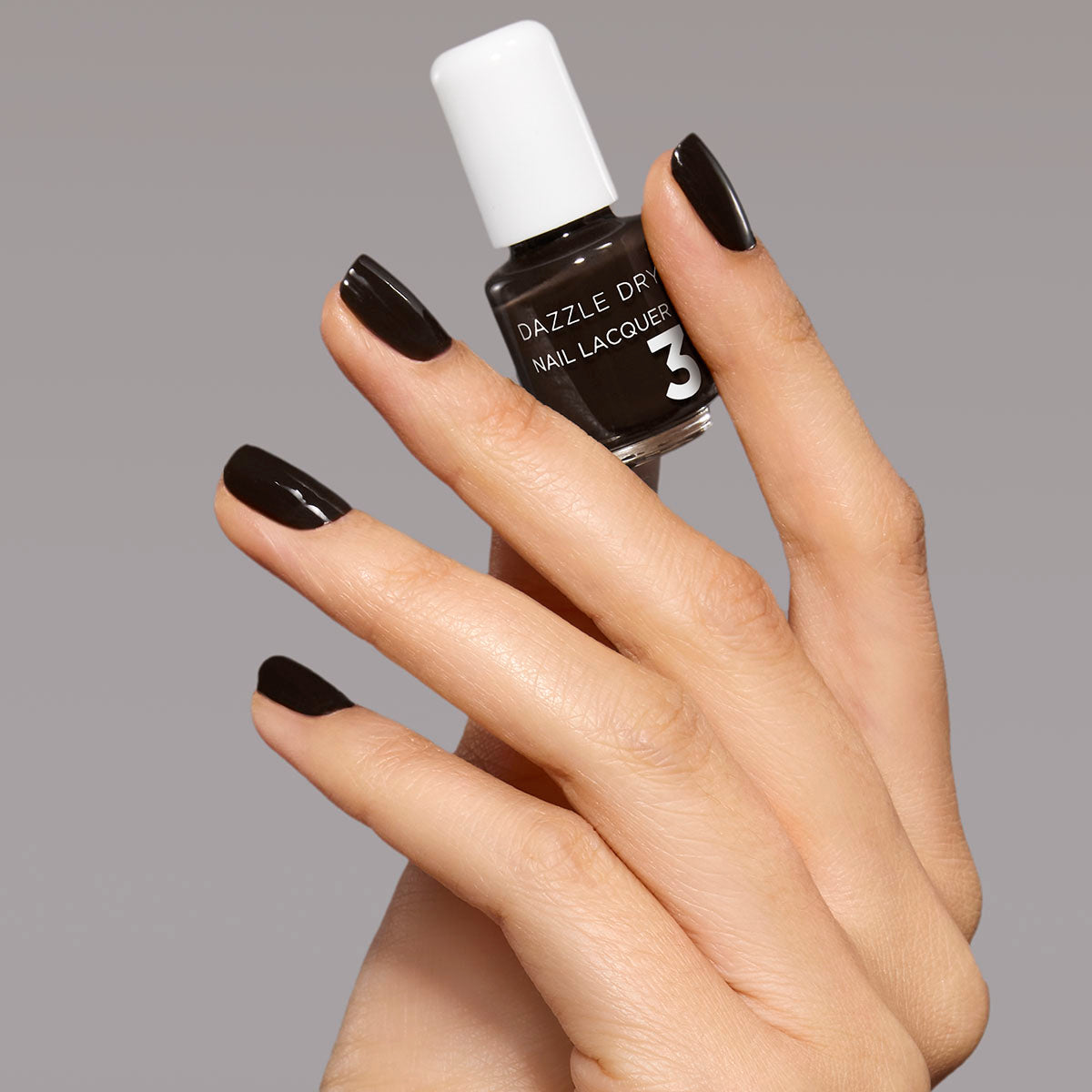 Hand with Haze painted on nails holding mini lacquer bottle