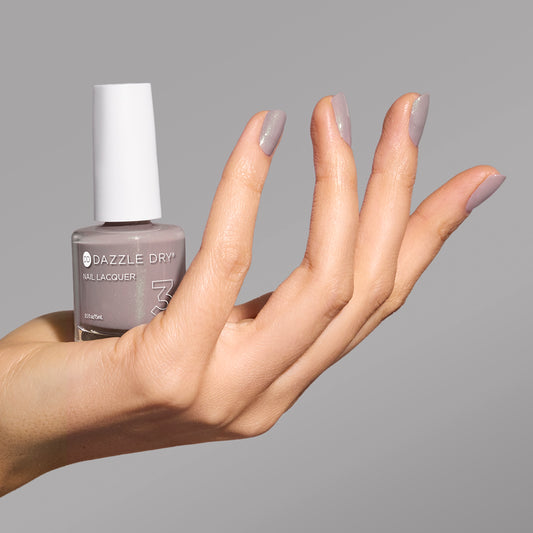 Hand with Let's Glow painted on nails holding lacquer bottle