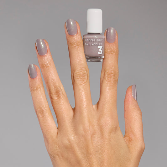 Hand with Let's Glow painted on fingernails holding mini nail polish bottle