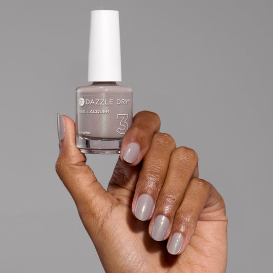 Hand with Let's Glow painted on nails holding lacquer bottle