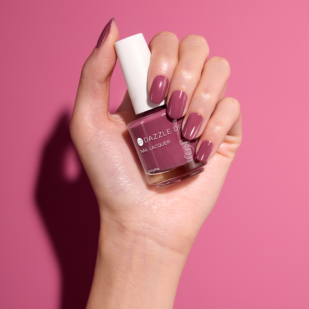 Hand with Take A Chance painted on nails holding lacquer bottle