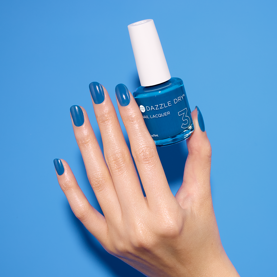 Hand with Memory Lane painted on nails holding Dazzle Dry nail lacquer bottle.