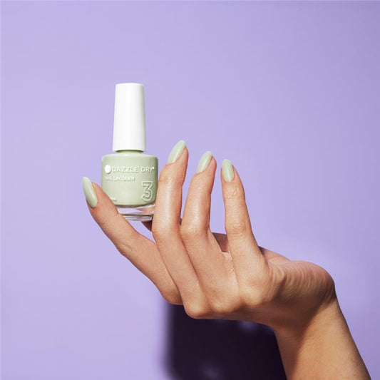 Hand with Honeydew painted on nails holding lacquer bottle