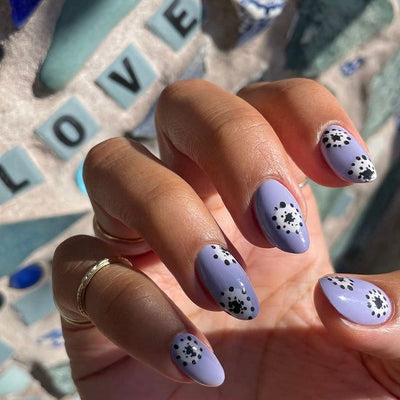 Hand with purple painted fingernails with black and white floral decoration